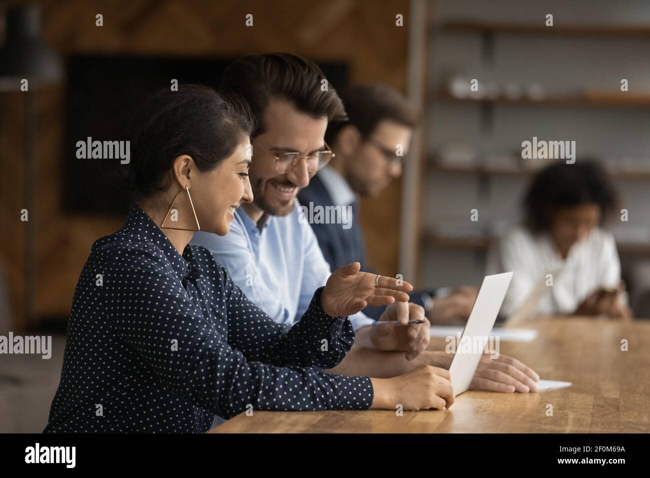 Smiling Indian businesswoman mentor training new employee, using laptop Stock Photo