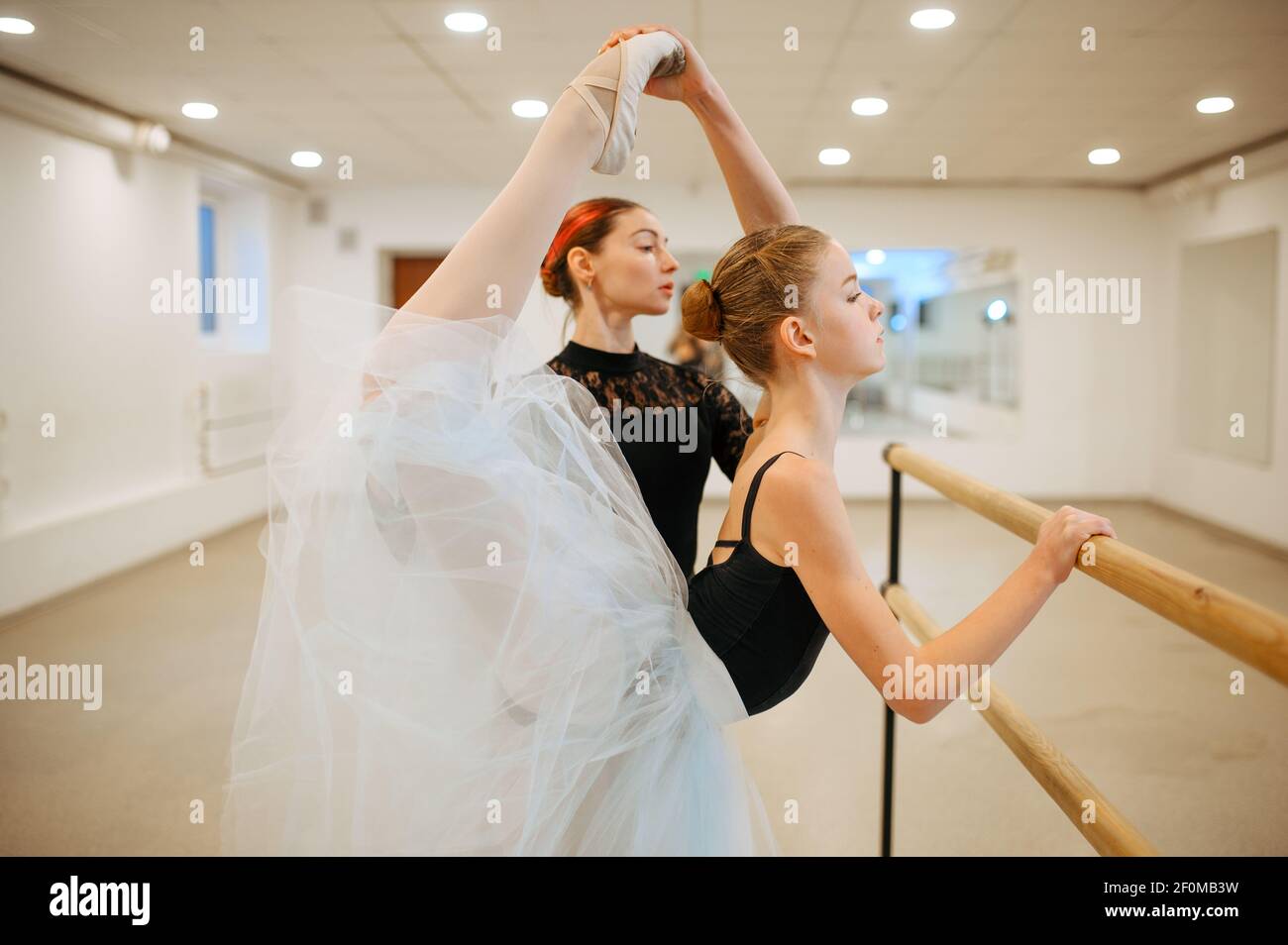 Teacher rehearsing with young ballerina at barre Stock Photo