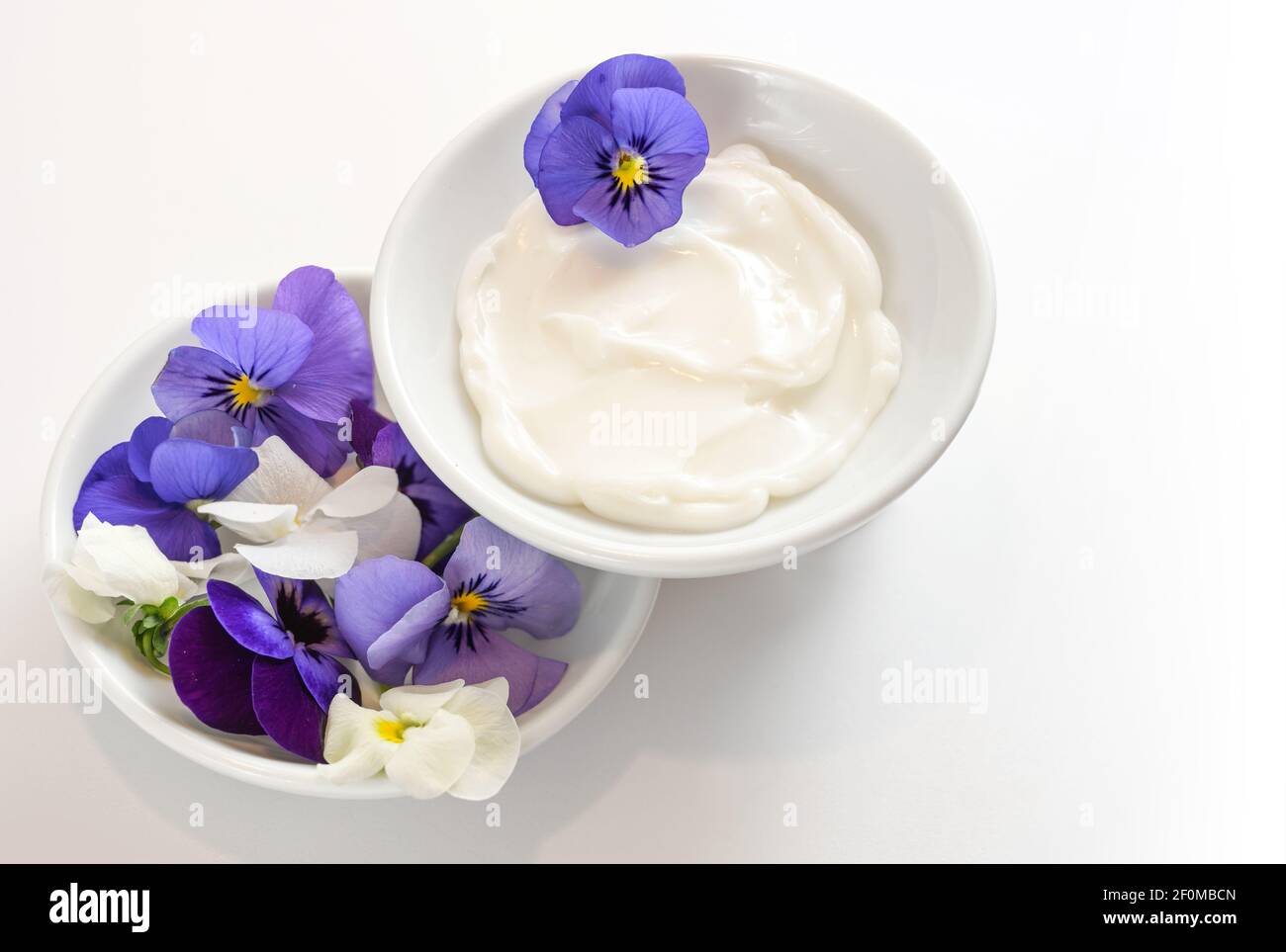 Natural balm from viola or violet flowers in white bowls, cosmetics concept, white gray background with copy space, selected focus Stock Photo
