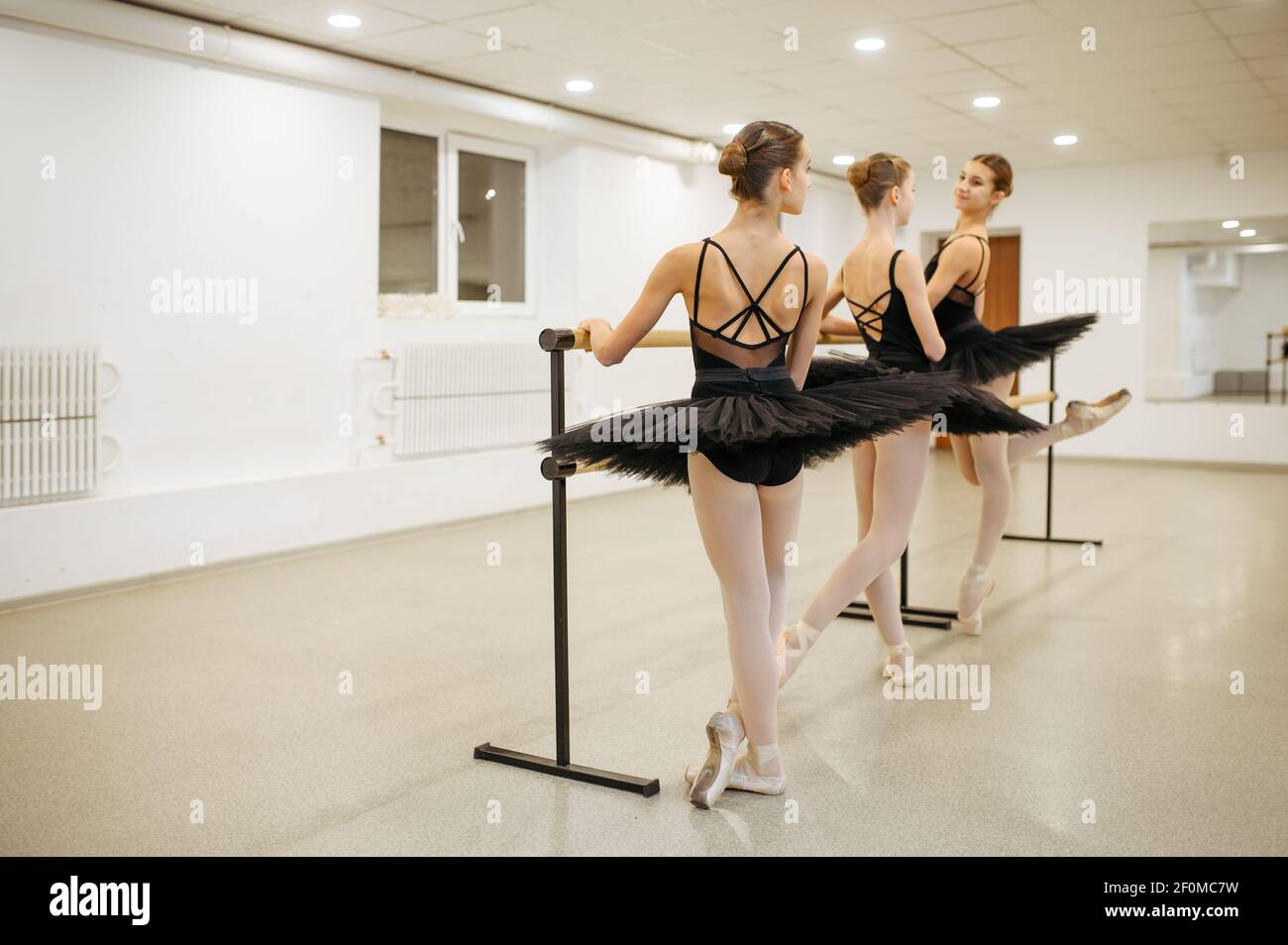 Elegant young ballerinas poses at barre in class Stock Photo