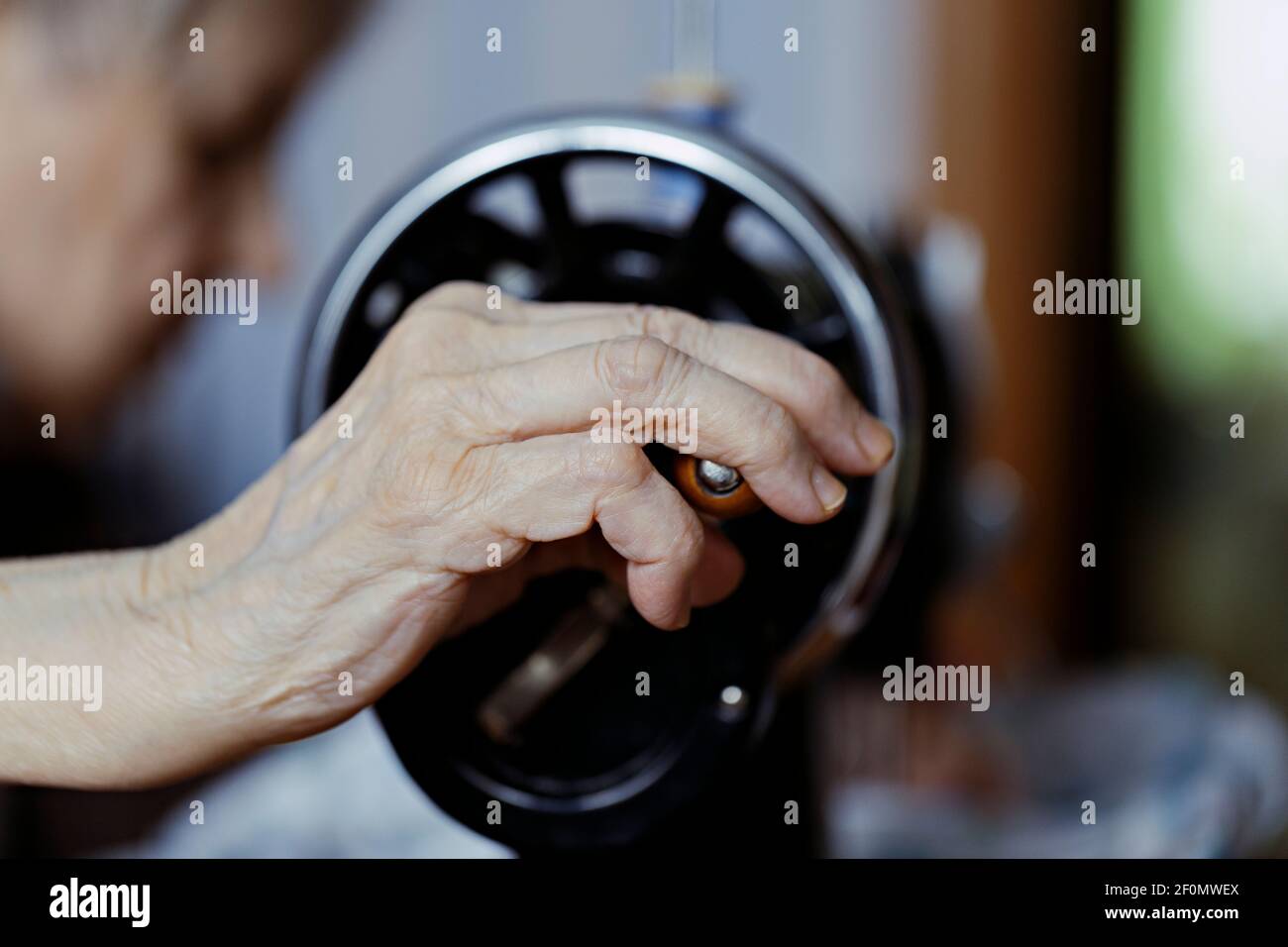 closeup of sewing on vintage sewing machine with senior female hands. selective focus photo Stock Photo