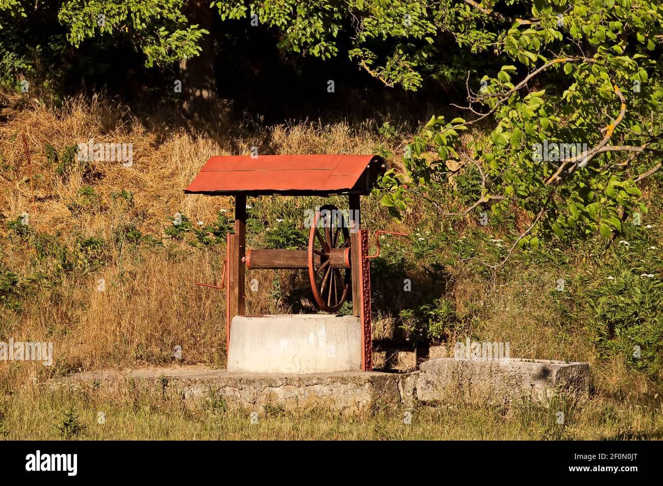 Well with concrete base and wooden construction near a village street, Nisovo, Bulgaria Stock Photo