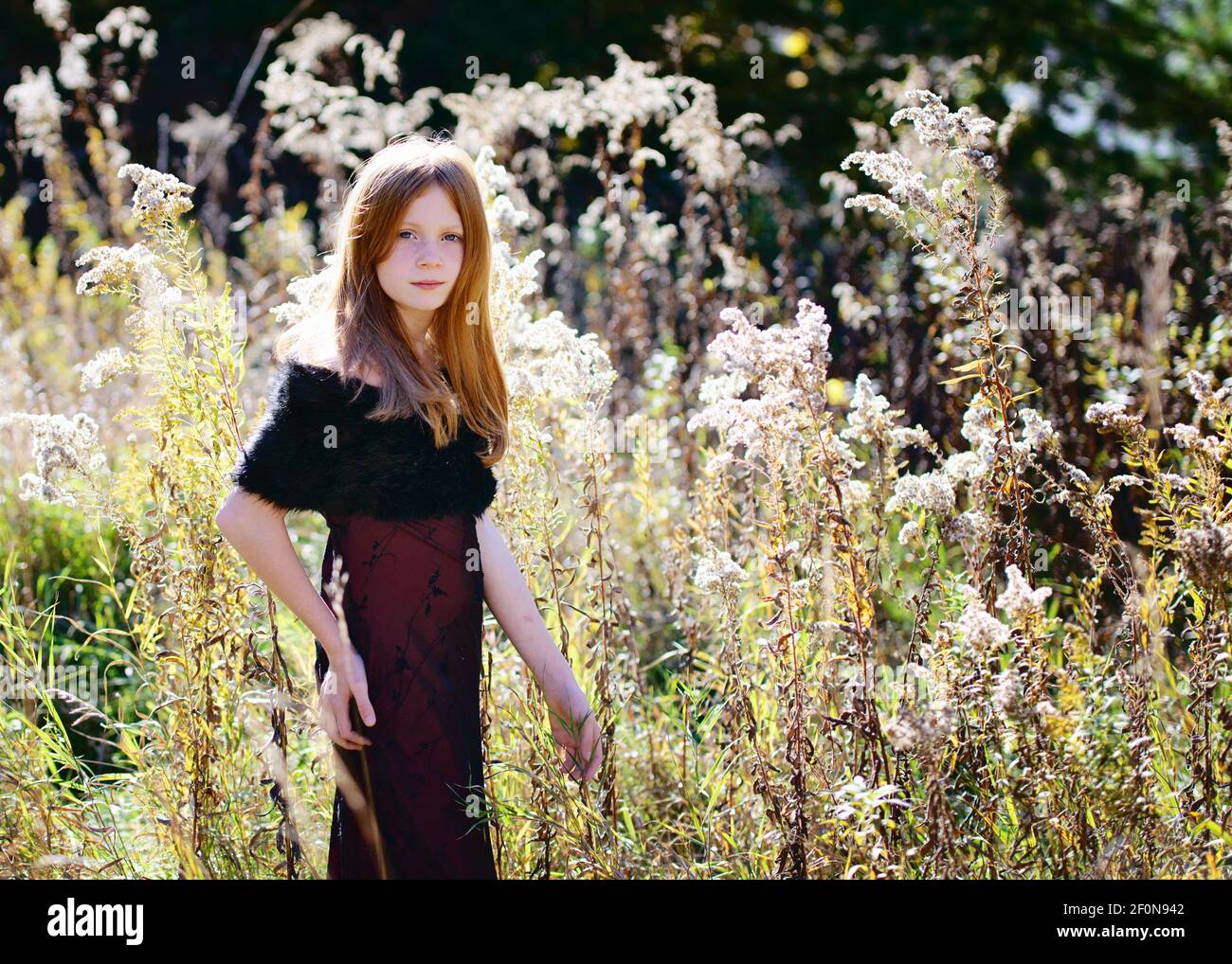Beautiful young girl with long red hair in red dress outdoors in Fall ...