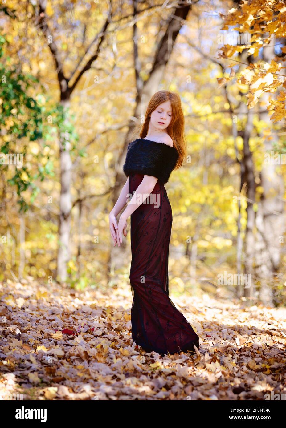Beautiful young girl with long red hair in red dress outdoors in Fall ...