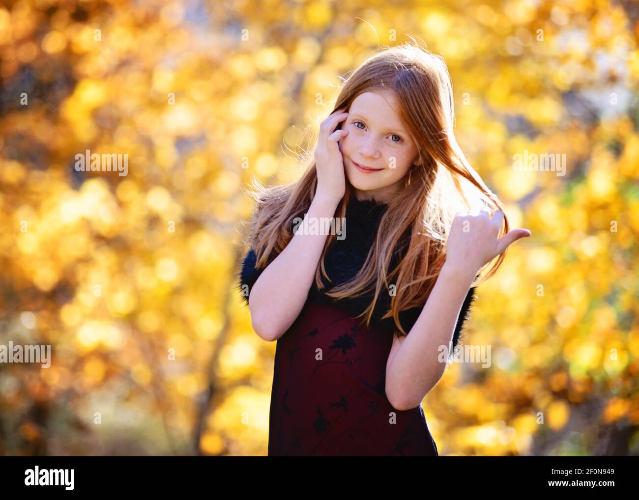 Beautiful young girl with long red hair in red dress outdoors in Fall ...