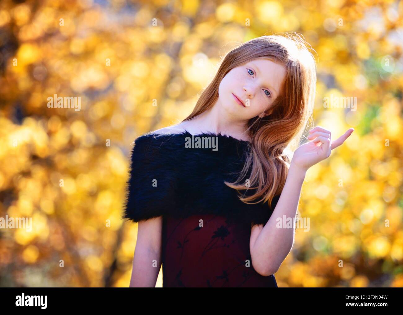 Beautiful young girl with long red hair in red dress outdoors in Fall ...