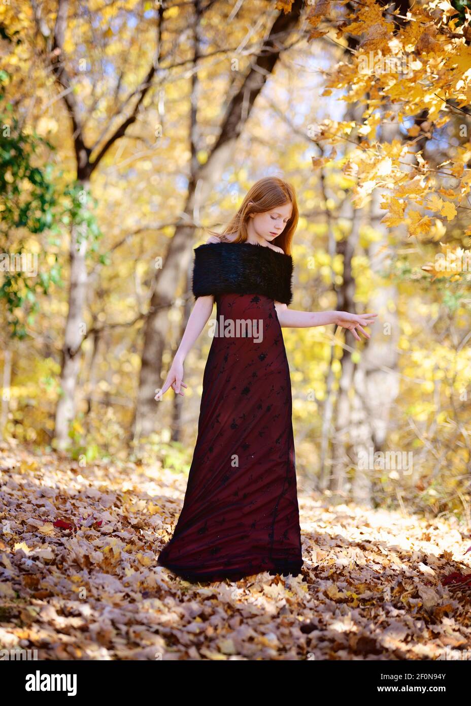 Beautiful young girl with long red hair in red dress outdoors in Fall ...