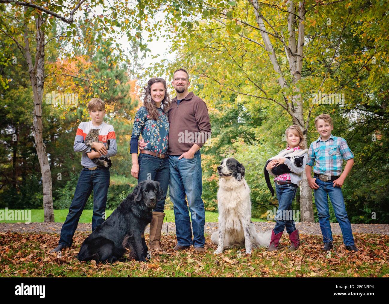 Happy family of five with dogs and cats by a country road. Stock Photo