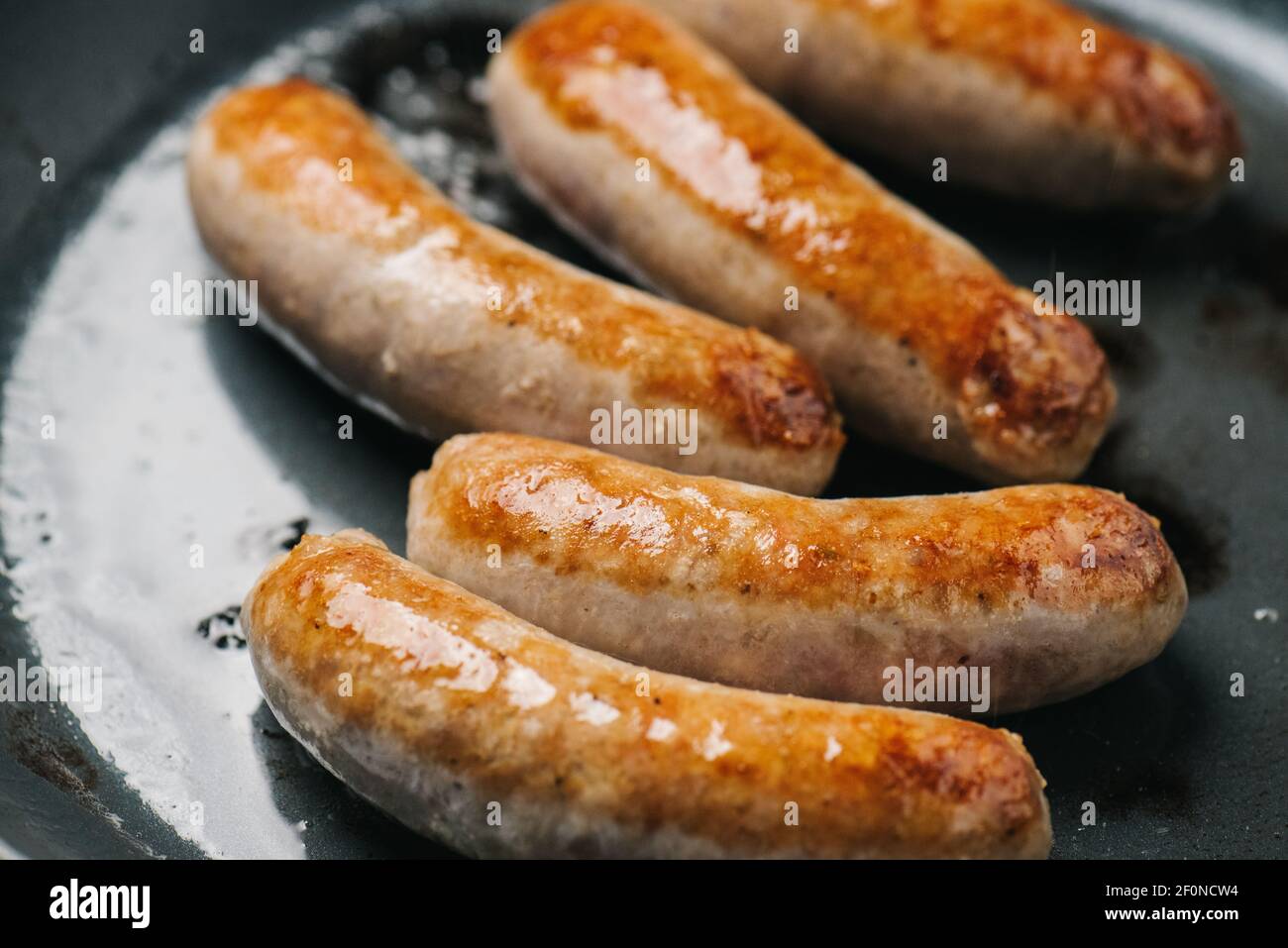 Closeup of Italian sausage links frying in a pan Stock Photo