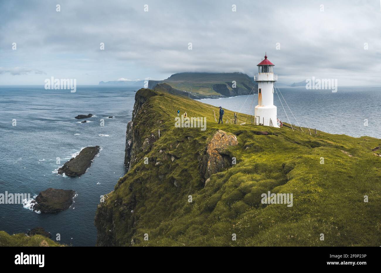 View Towards Lighthouse on the island of Mykines Holmur, Faroe Islandson a cloudy day with view towards Atlantic Ocean. Stock Photo