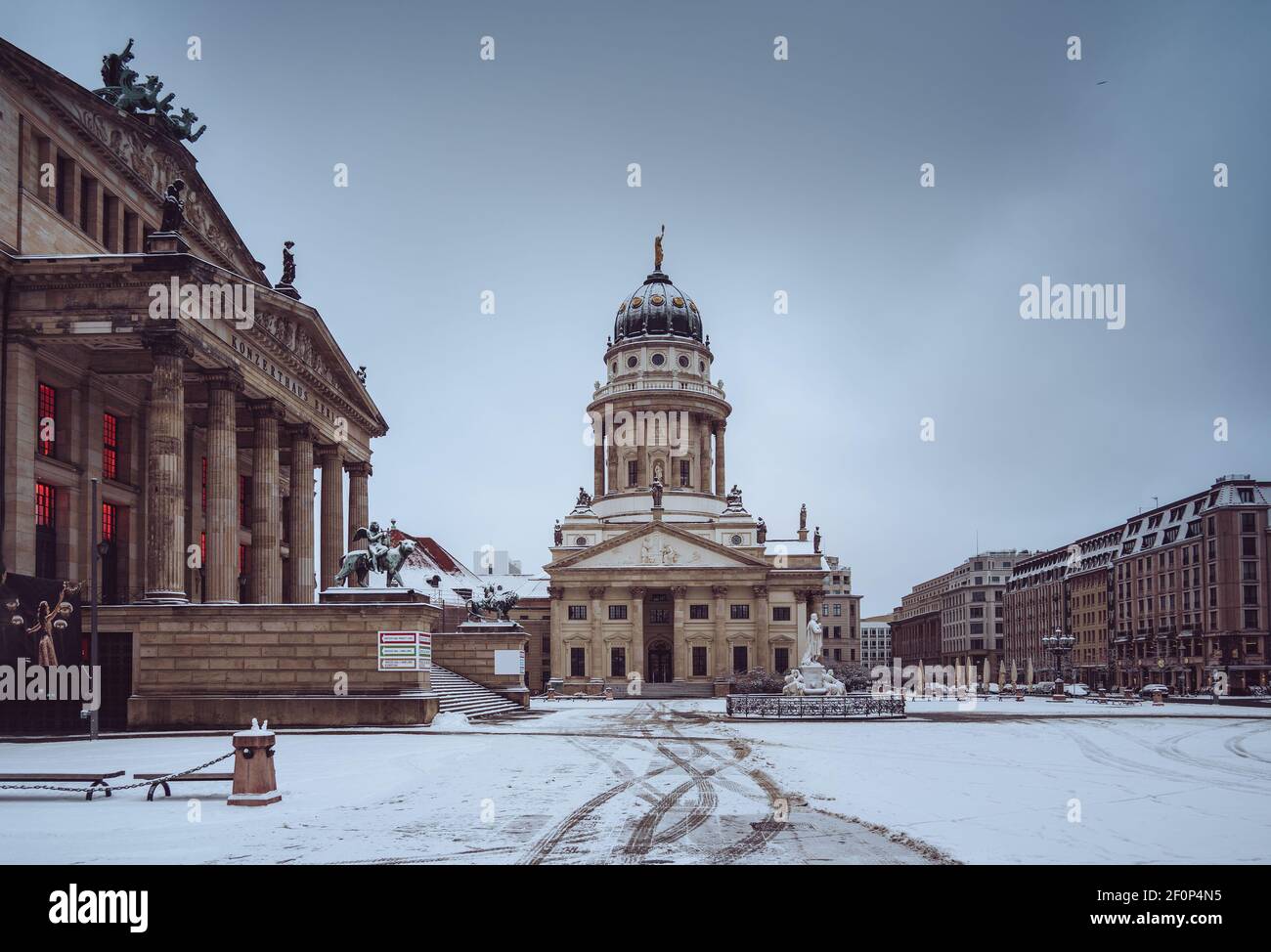 Snow and winter panoramic view of famous Gendarmenmarkt square with Berlin Concert Hall and German Cathedral. Early morning light with clouds after Stock Photo