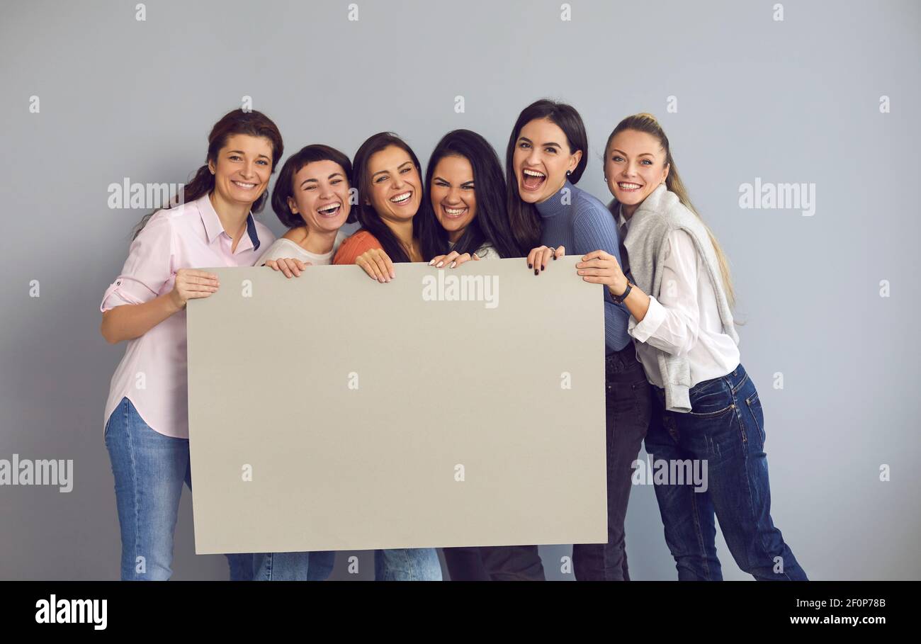Group of happy women standing in studio, laughing and holding empty ...