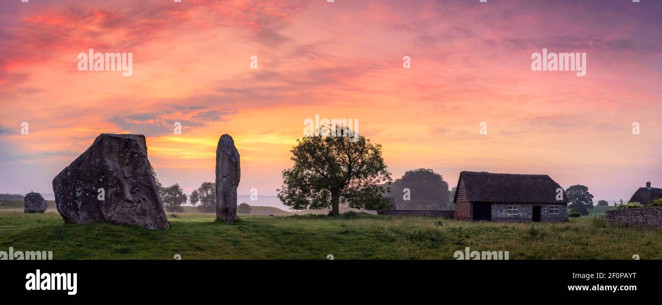 The day before the Summer Solstice, just after 4am, the moon fades as the sun rises behind the ancient Sarsen stones, at Avebury in Wiltshire. The Ave Stock Photo