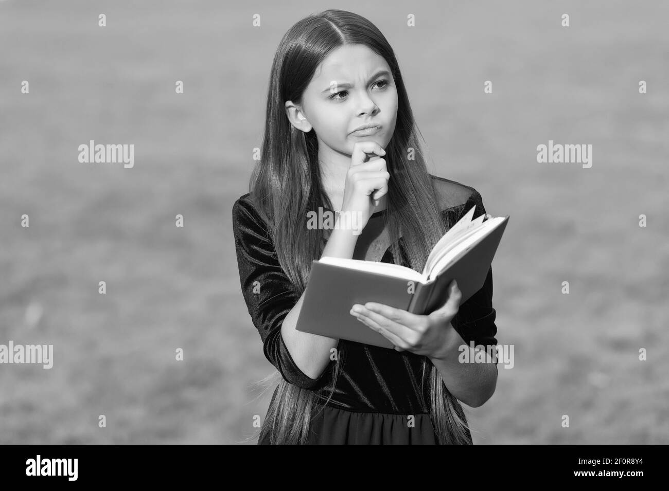 Think clearly and rationally. Serious child think holding book green grass. Critical and creative thinking skills. Making decision. Doing homework assignment. Intellectual growth. Education school. Stock Photo