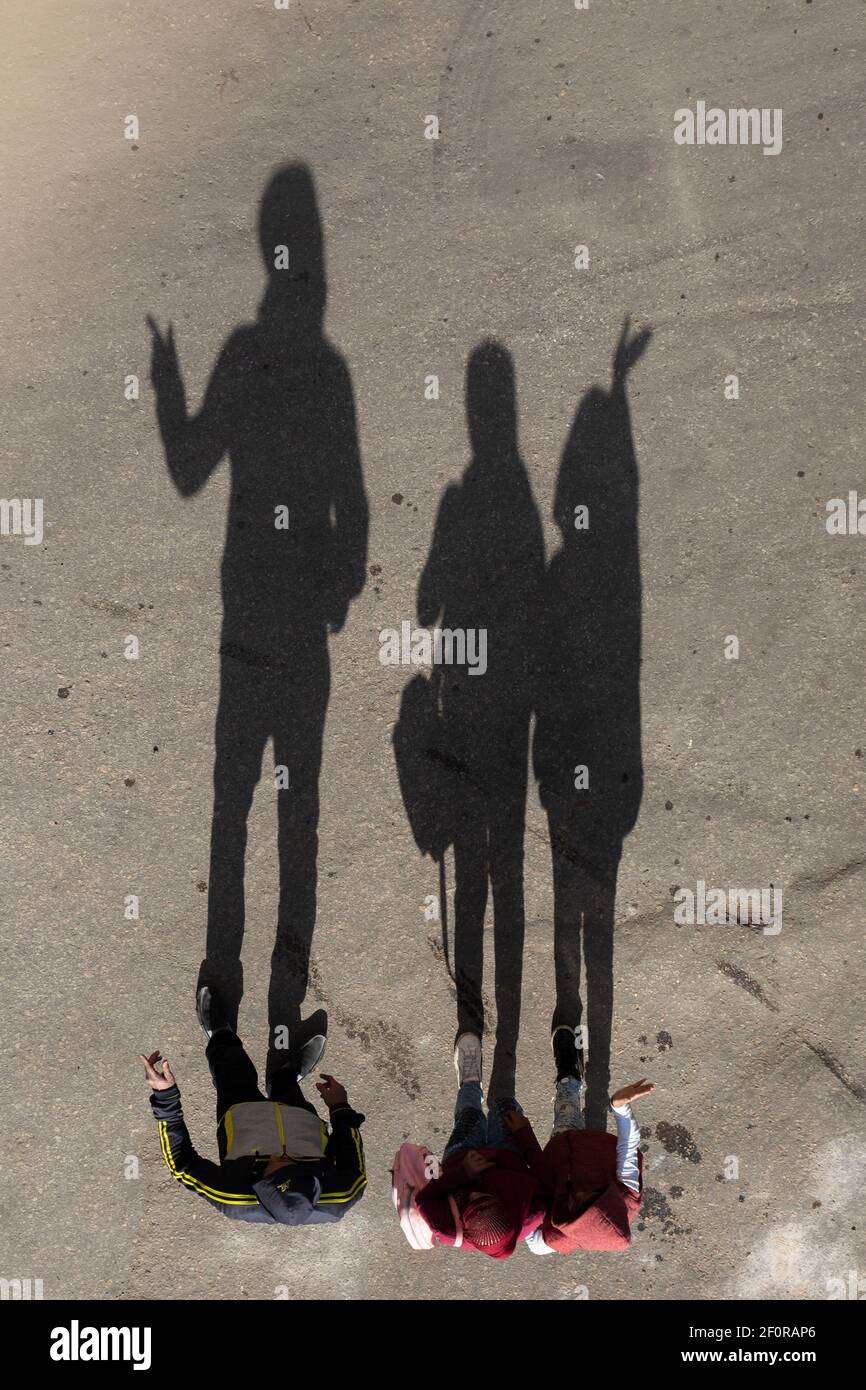 Aerial view of shadows of three people gesturing directions, Cairo, Egypt Stock Photo