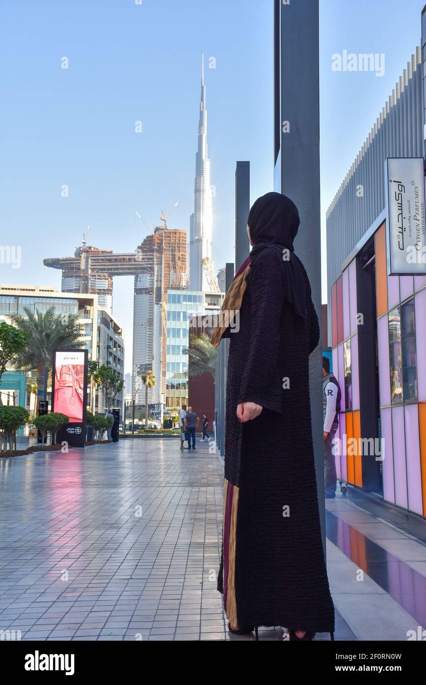 Arab young woman wearing abaya standing in the city walk Dubai and in background Burj Khalifa Stock Photo