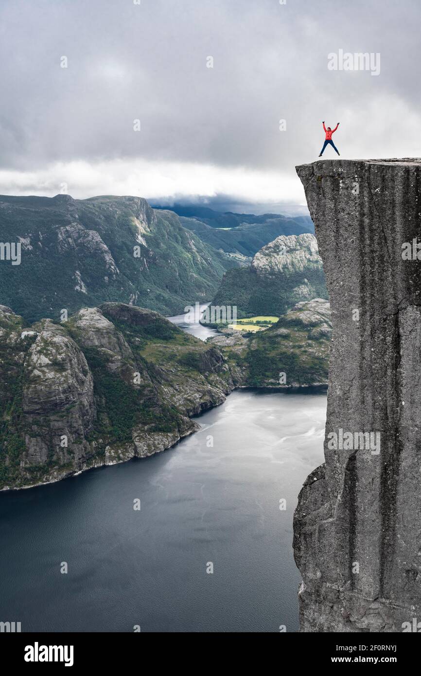 Person jumps into the air, steep cliff, Preikestolen rock pulpit, Lysefjord, Ryfylke, Rogaland, Norway Stock Photo
