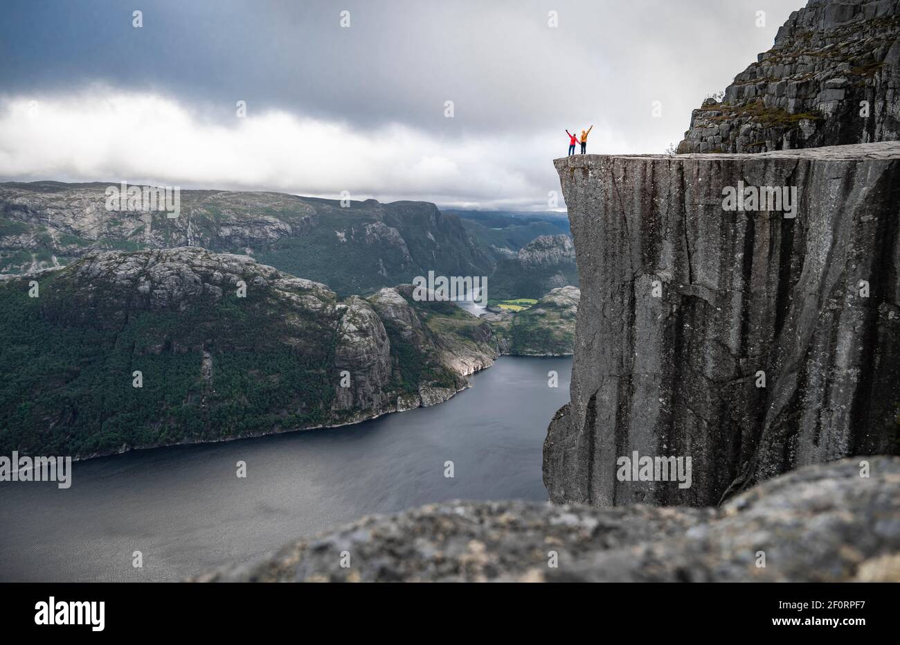Two people at rock plateau, Preikestolen rock spire, Lysefjord, Ryfylke, Rogaland, Norway Stock Photo