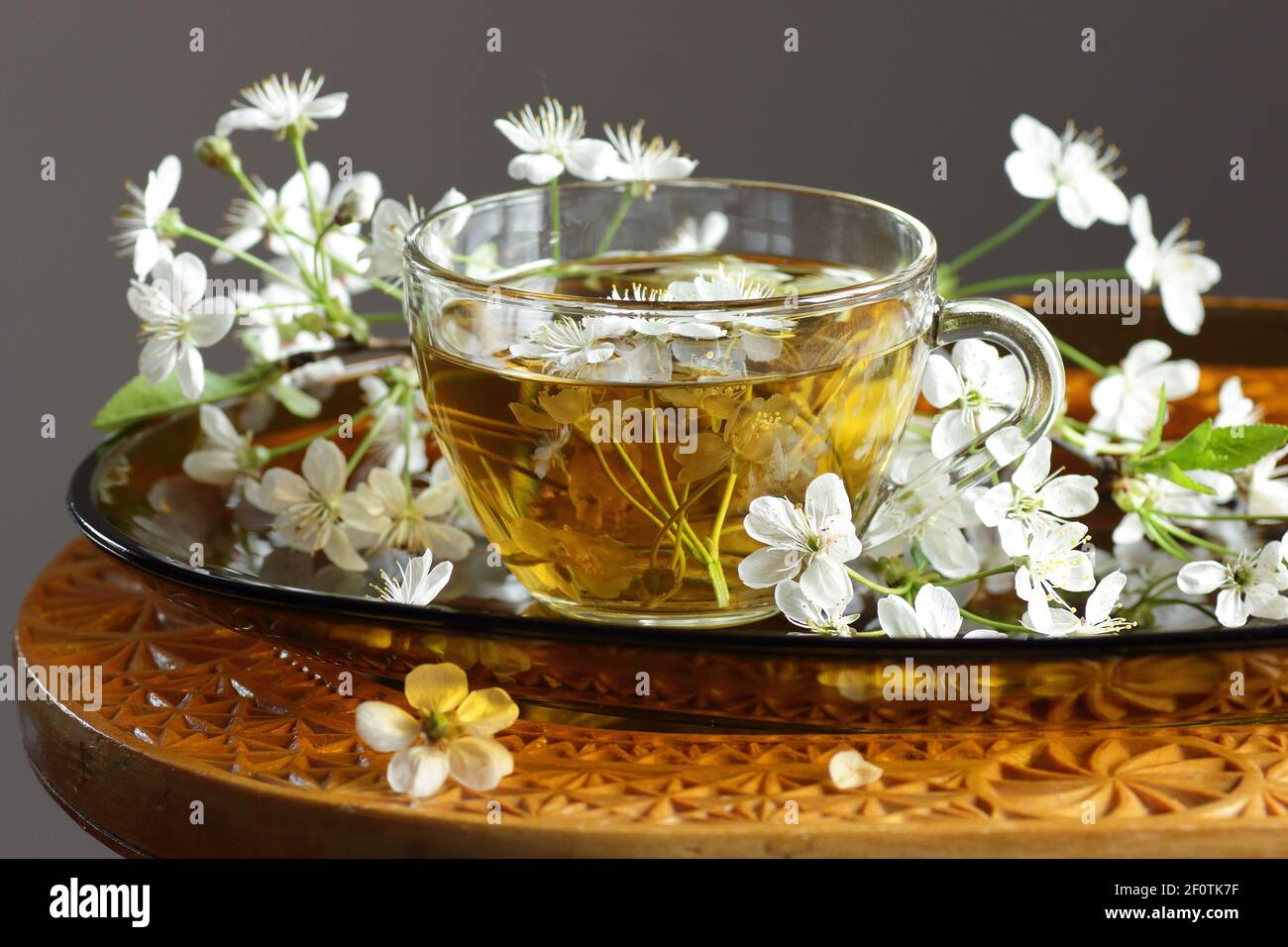 Cherry blossom tea in a glass cup with blooming floral branches nearby, healthy herbal drink is good for skin and heart, rich of antioxidants and esse Stock Photo