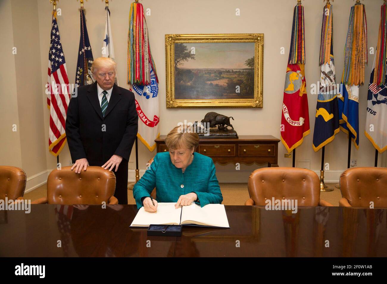 President Donald Trump accompanies German Chancellor Angela Merkel as she signs the guest book Friday March 17 2017 in the Roosevelt Room during her official visit to the White House in Washington D.C. Stock Photo