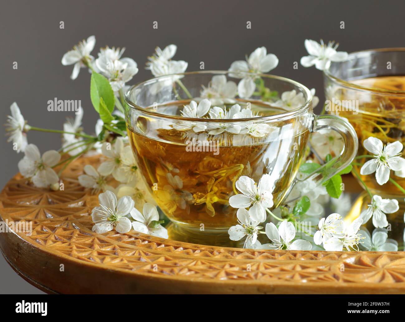 Cherry blossom tea in a glass cup with blooming floral branches nearby, healthy herbal drink is good for skin and heart, rich of antioxidants and esse Stock Photo