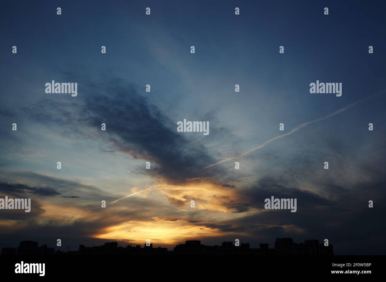 Colorful dramatic sky with clouds at sunset. City during warm sunset ...