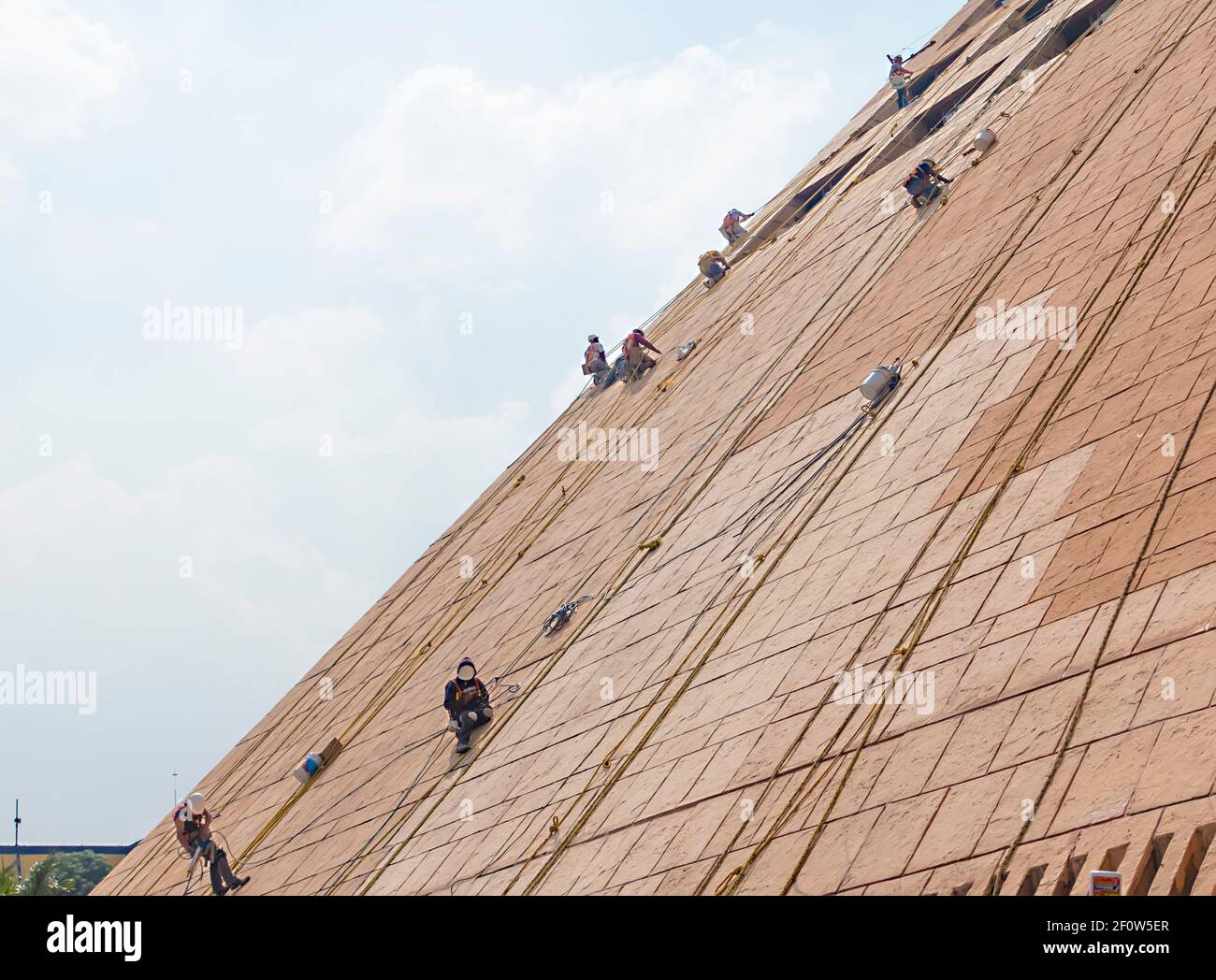 Cleaners on sloping facade of building Stock Photo