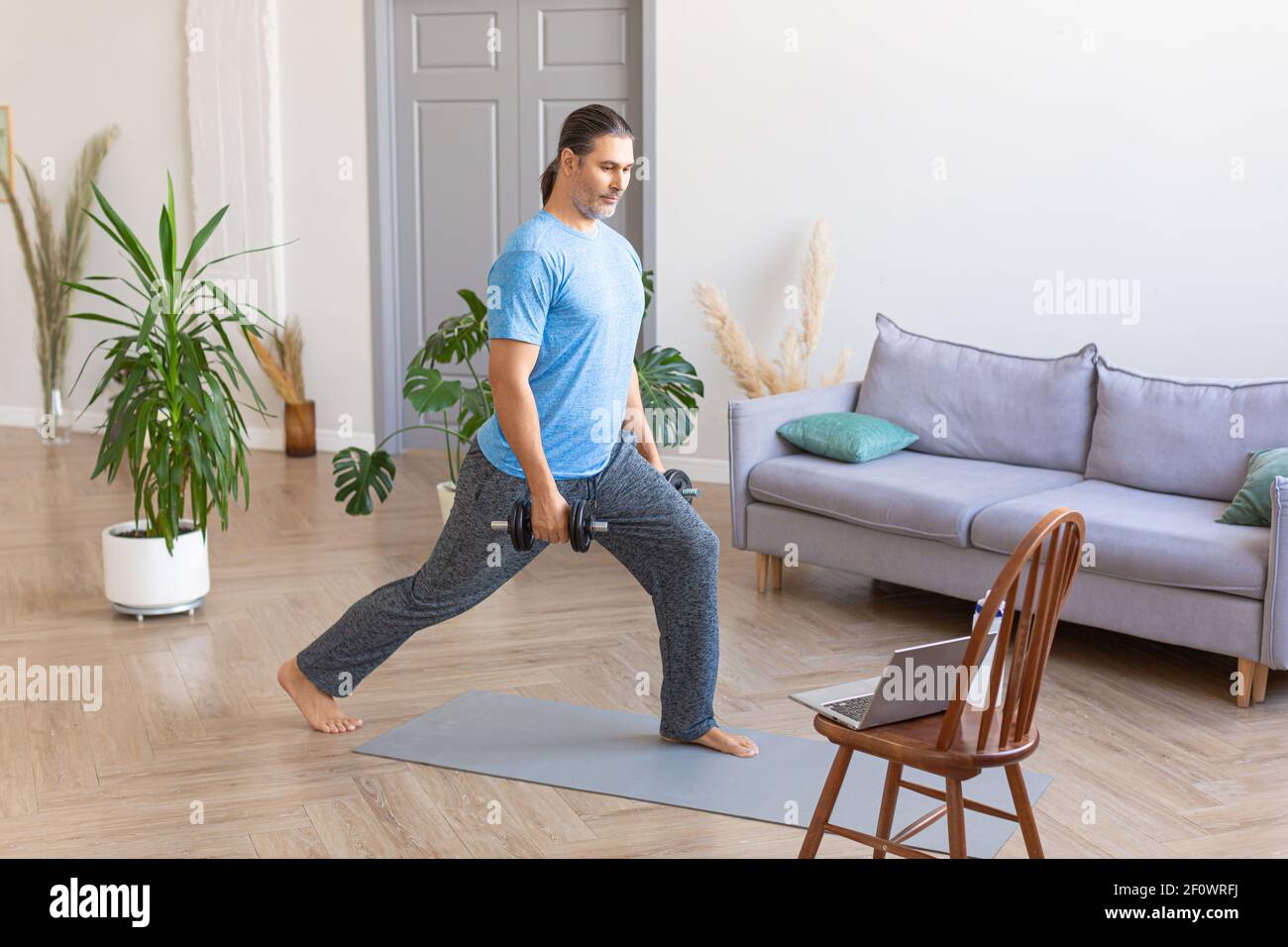 Photo of a man trains at home online using a tutorial from the