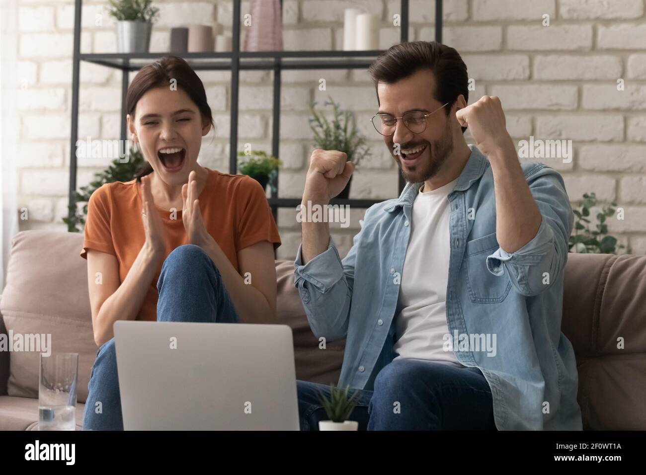 Overjoyed young husband wife scream yes as winners by laptop Stock Photo