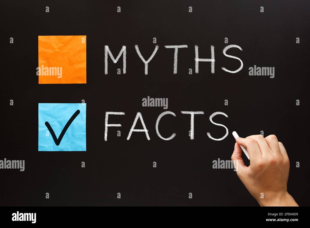 Hand writing Myths or Facts concept with white chalk on blackboard. Choose the Facts over the Myths. Stock Photo