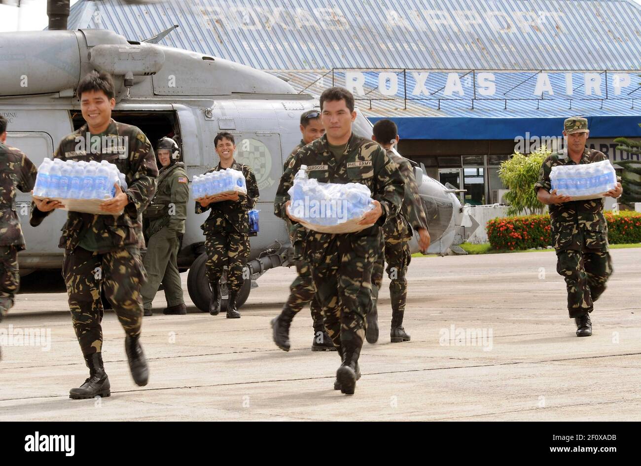 26 June 2008 - Philippines - Servicemen of the Philippine Army transport bottled water from an SH-60 helicopter assigned to Helicopter Anti-Submarine Squadron (HS) 4 at Roxas airport. The U.S. Navy and the Philippine Army and Air Force have been working side by side during disaster relief efforts in the wake of Typhoon Fengshen. At the request of the government of the Republic of the Philippines, the Nimitz-class aircraft carrier USS Ronald Reagan (CVN 76) is off the coast of Panay Island providing humanitarian assistance and disaster response. Ronald Reagan and other U.S. Navy ships are opera Stock Photo