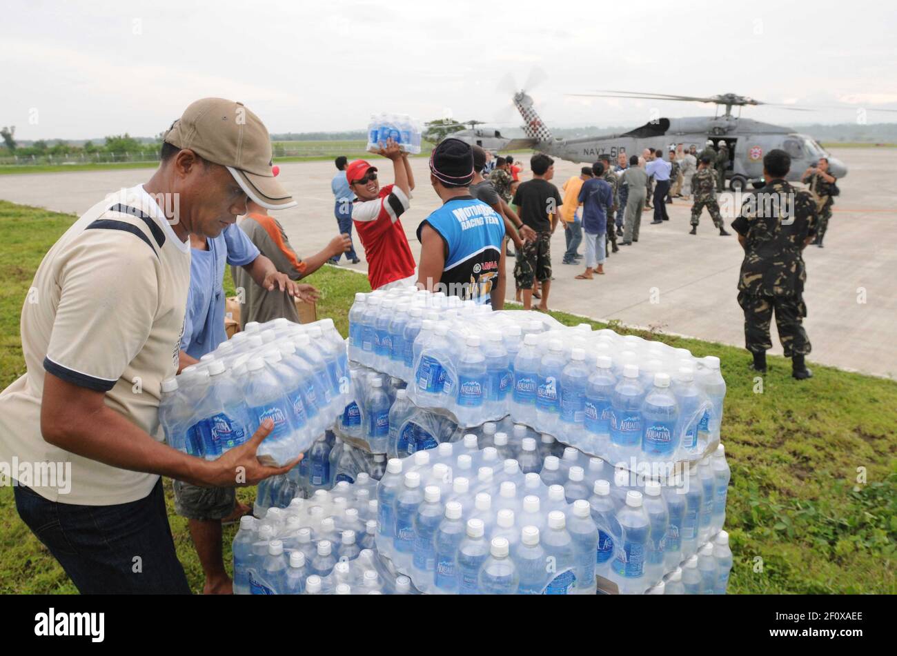 26 June 2008 - Philippines - Residents of Iloilo help U.S. service members unload bottled water and rice from a helicopter assigned to the Ã’Black KnightsÃ“ of Helicopter Anti-Submarine Squadron (HS) 4 on a flight line in Iloilo. The Ronald Reagan Carrier Strike Group is providing humanitarian assistance and disaster relief to victims of Typhoon Fengshen, which struck the Philippines June 23, 2008. Photo Credit: Spike Call/U.S. Navy/Sipa Press/0806271620 Stock Photo