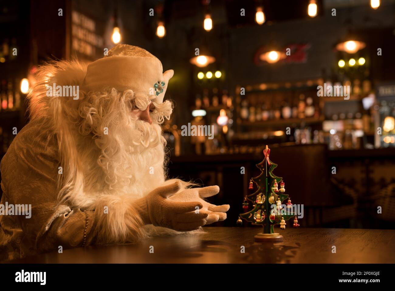 Thoughtful Santa Claus pray for little christmas tree Stock Photo