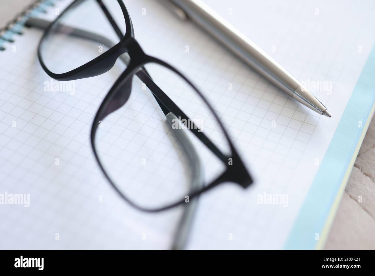 Black-framed glasses, pen, notebook lie on table Stock Photo