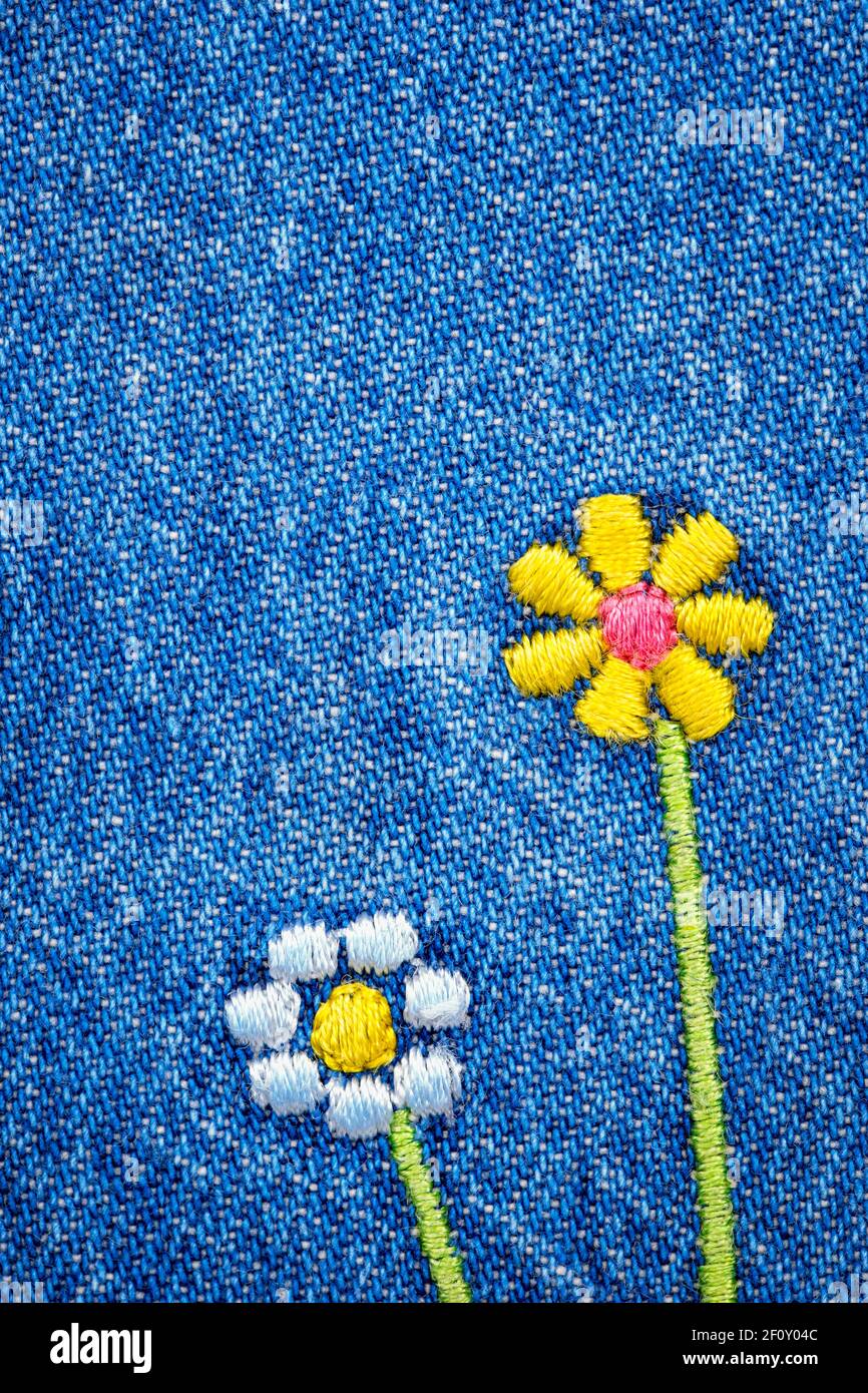 Embroidered flowers on fragment of  blue denim jeans texture Stock Photo