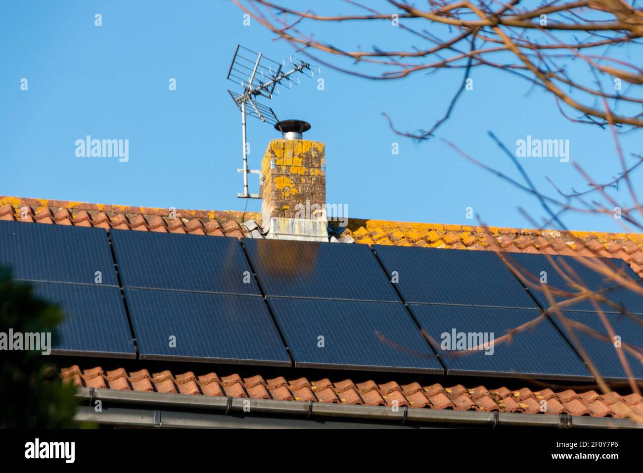 a close up view of a chimney on a residential roof with solar panels ...