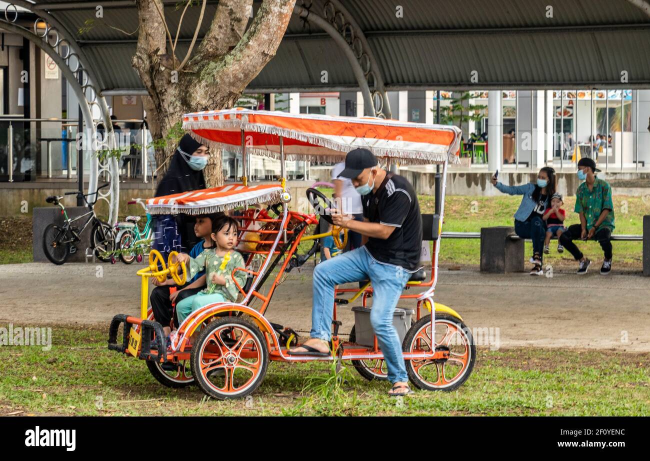Local people having fun jogging on cycles and quad cycles at Likas Bay Borneo Malaysia Stock Photo