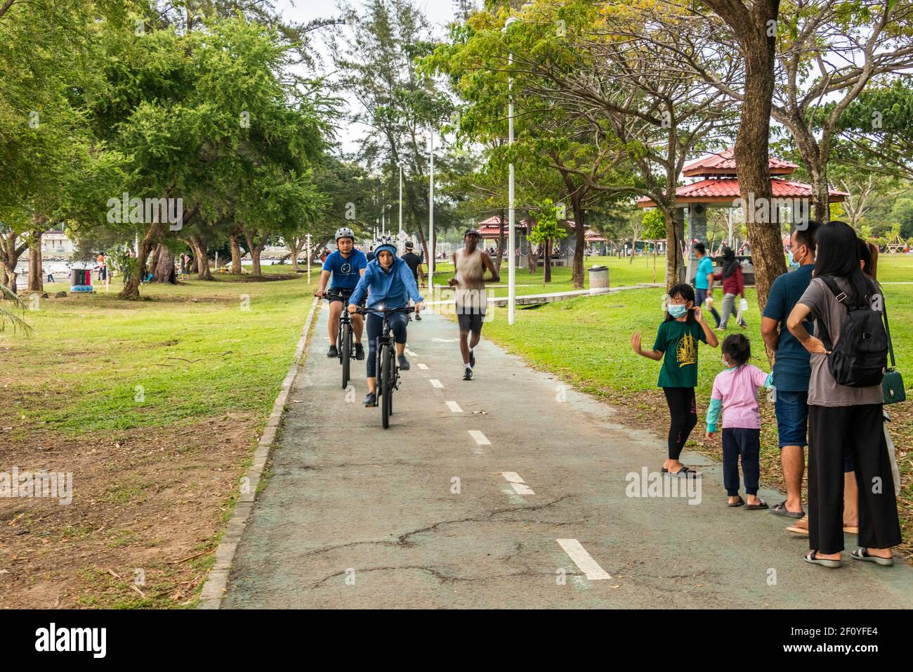 Local people having fun jogging on cycles and quad cycles at Likas Bay Borneo Malaysia Stock Photo