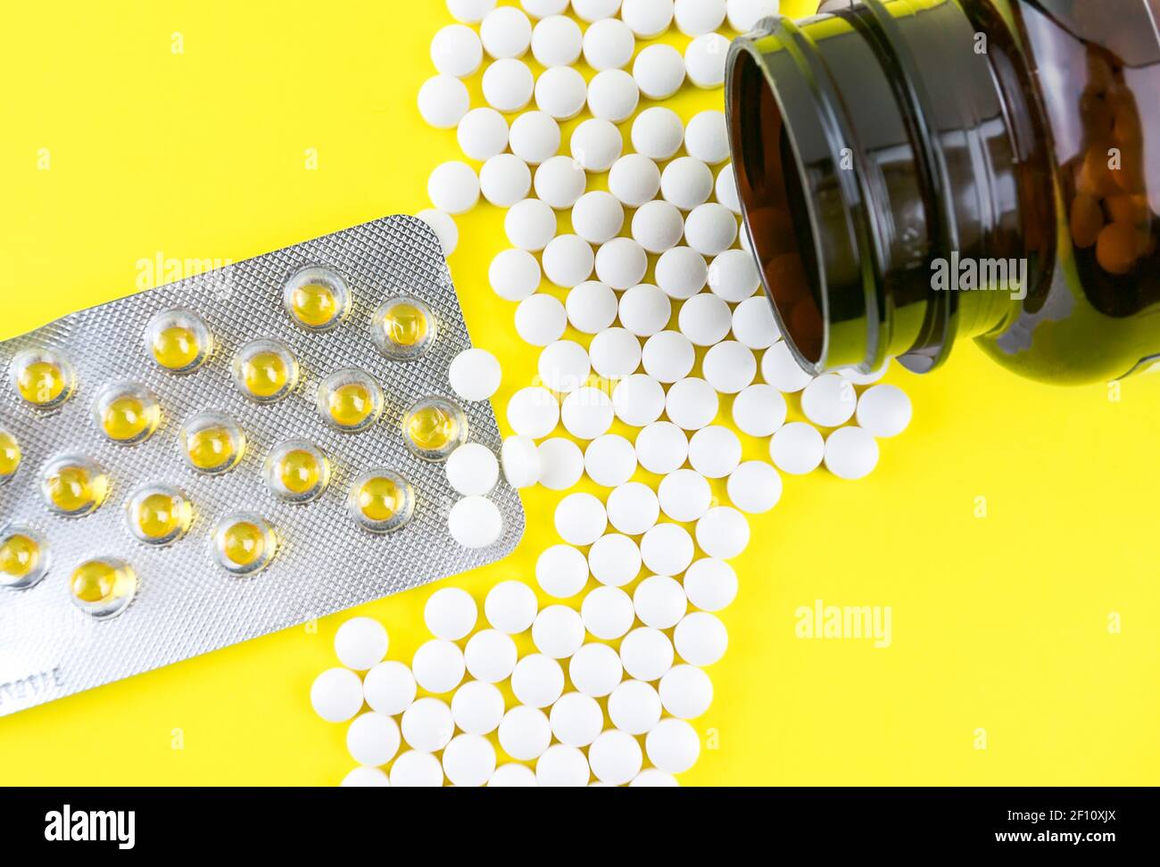 Many gel capsules of vitamin D3 2000 IU and Vitamin K2 pills on yellow background Stock Photo