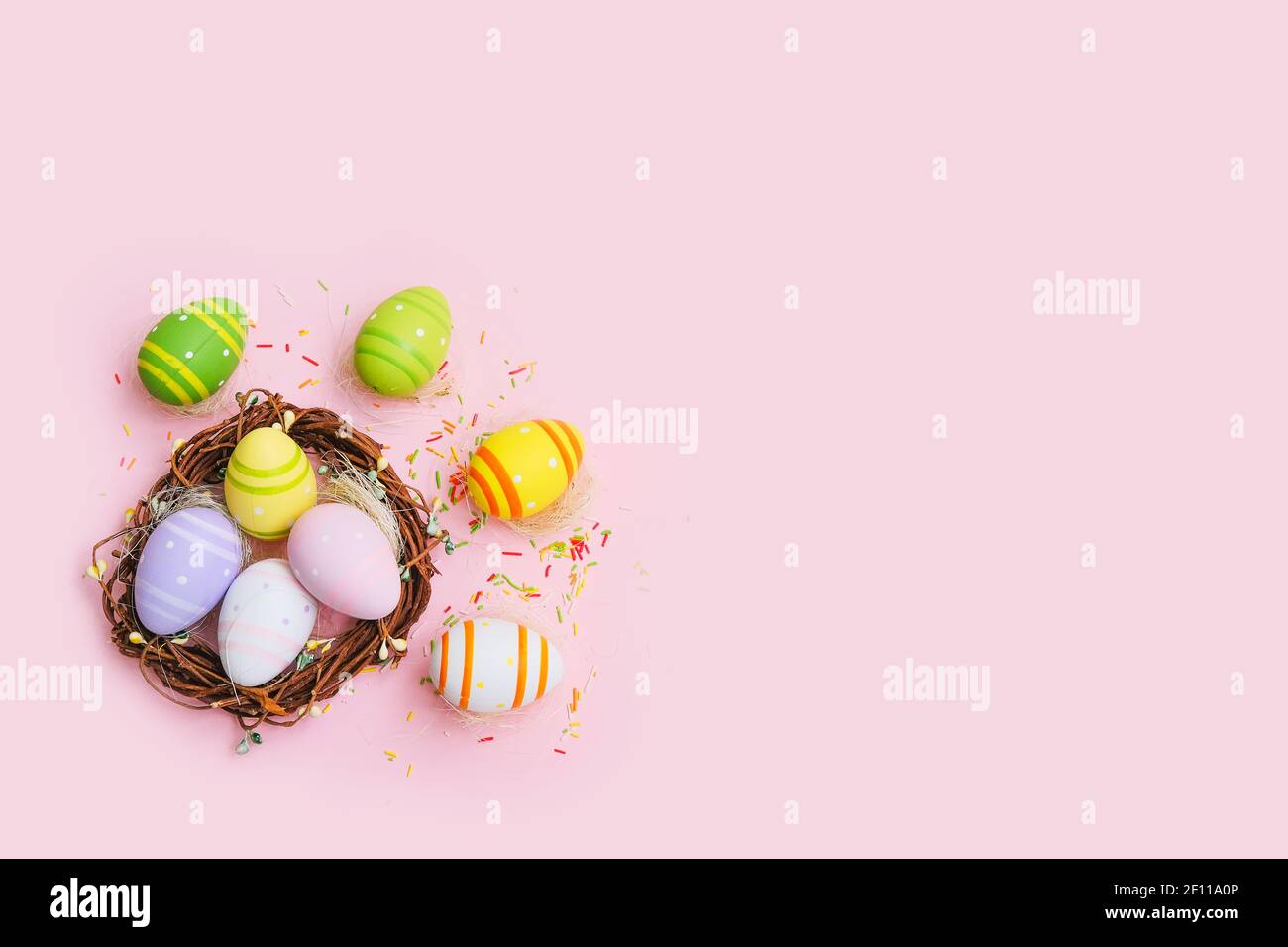 Colorful easter eggs in nest on pastel pink background. Copy spase ...