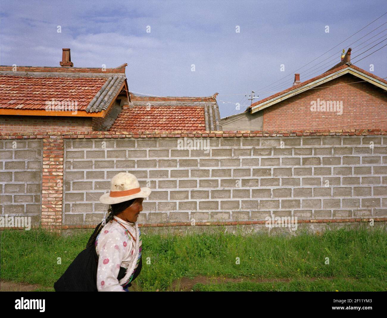 A Tibetan woman walking past newly built houses. (Photo by Raphael Fournier/Sipa USA) Stock Photo