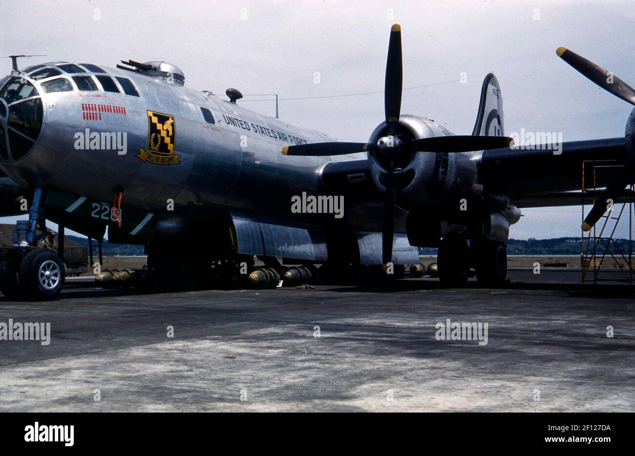 Three-quarter left front view of a Boeing B-29 Superfortress with bombs sitting underneath aircraft. Nose art includes nickname 'Force for Freedom' with symbol, and number of bomb missions represented as bombs. Stock Photo