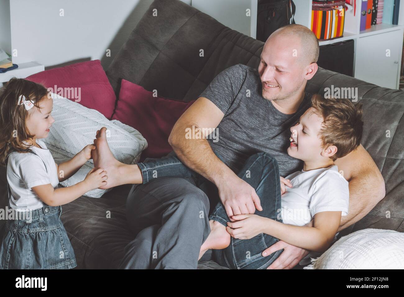 Father laughs and plays with his children. Man with his son and daughter having fun at home. Stock Photo