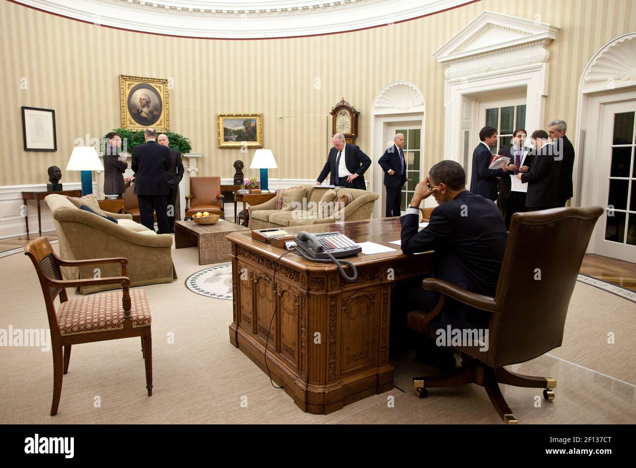 President Barack Obama works on a statement to the press after a phone call with Egyptian President Hosni Mubarak in the Oval Office Jan. 28 2011. Vice President Joe Biden center right and members of the national security team work with the President. Stock Photo