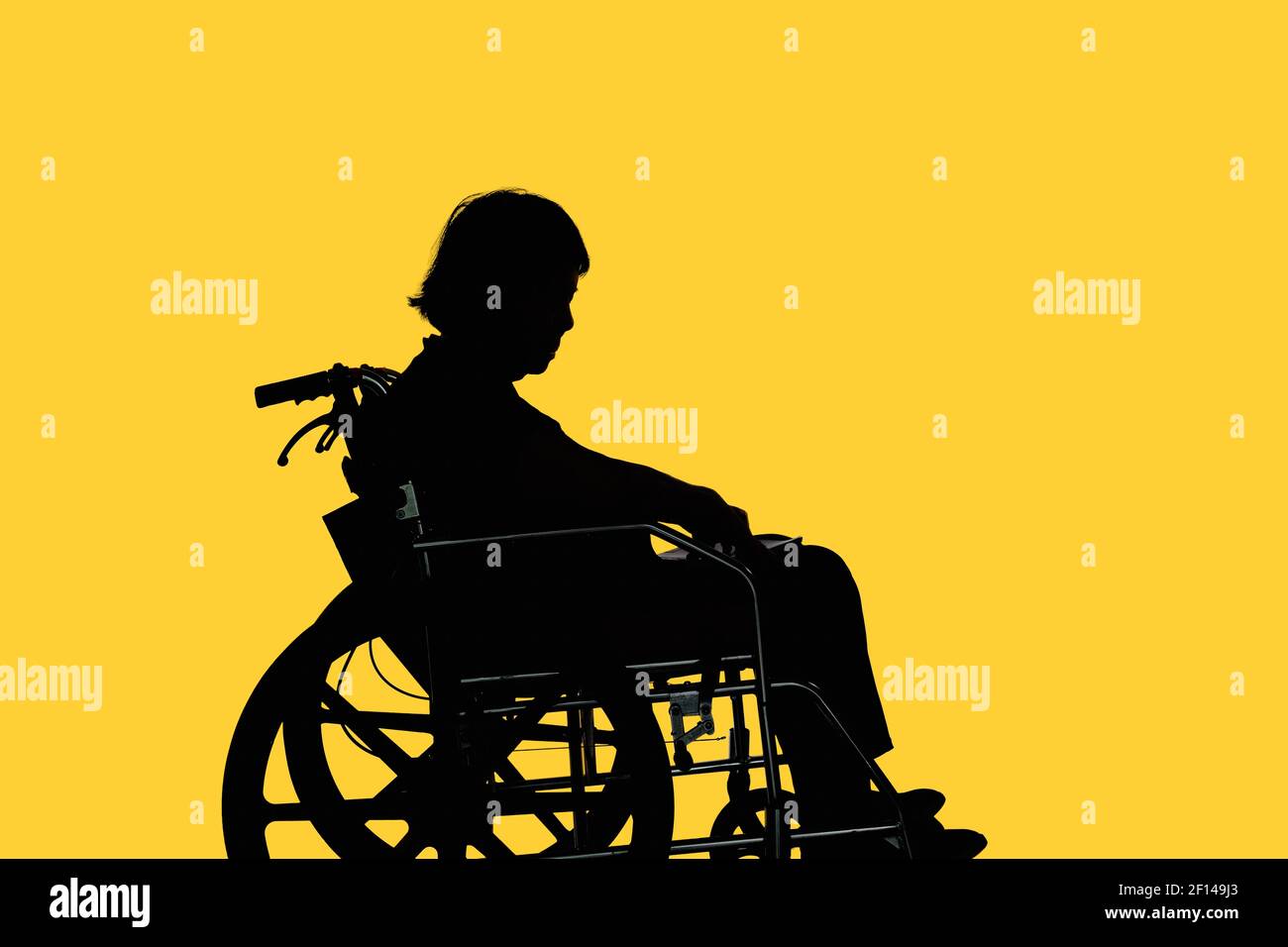 Silhouette of Disabled and dejected elderly woman sitting in her wheelchair Stock Photo