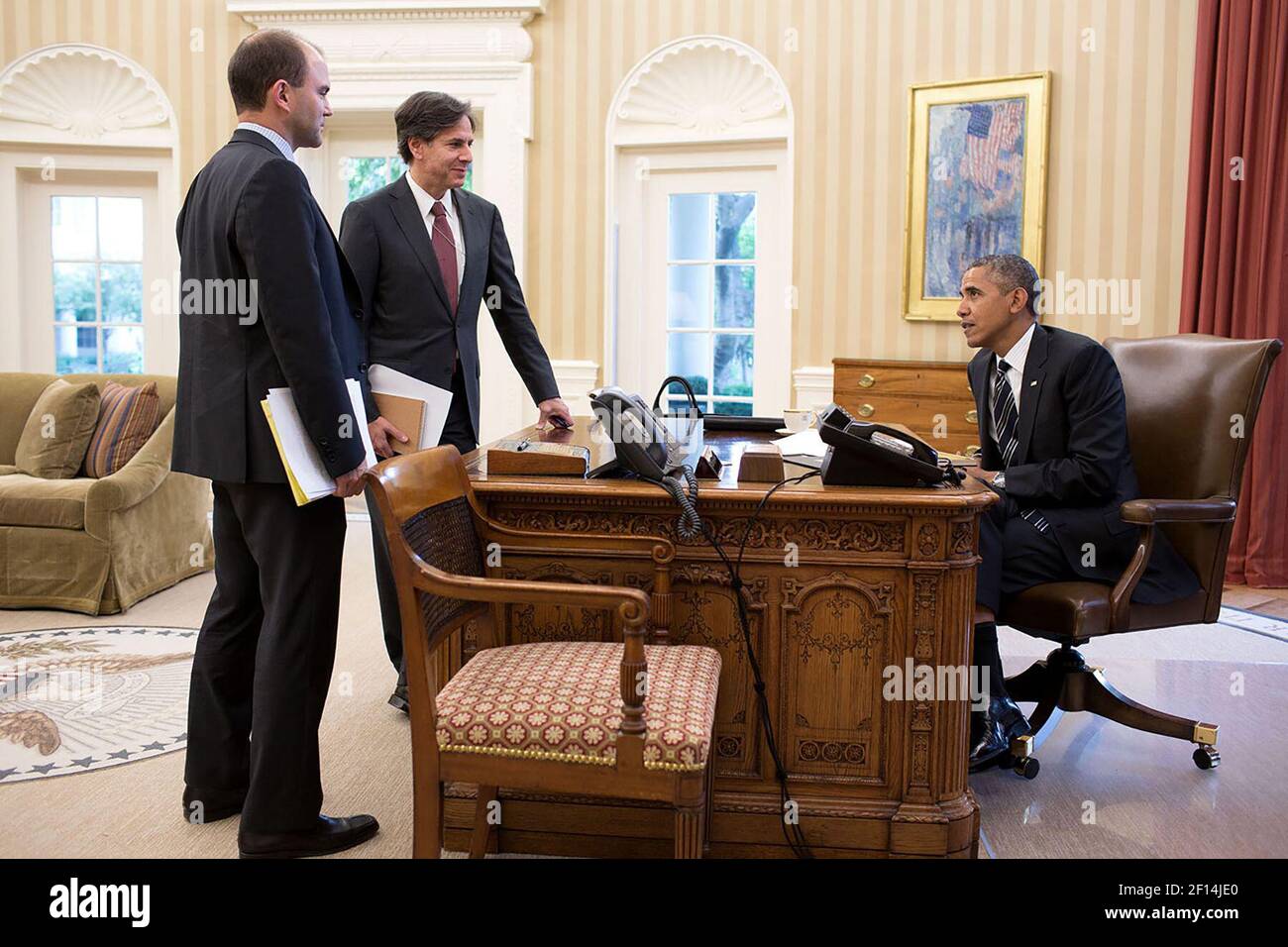President Barack Obama talks with Ben Rhodes, left, and Anthony Blinken prior to a phone call in the Oval Office, Sept. 27, 2013 Stock Photo
