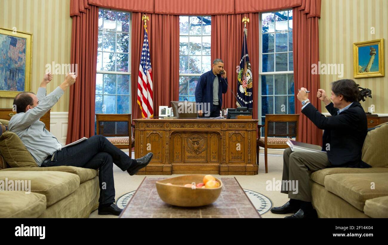 Ben Rhodes and Anthony Blinken both give thumbs up as the President talks on the phone with Secretary of State John Kerry. The call was on a Saturday which accounts for the casual attire ca. Nov. 23, 2013 Stock Photo