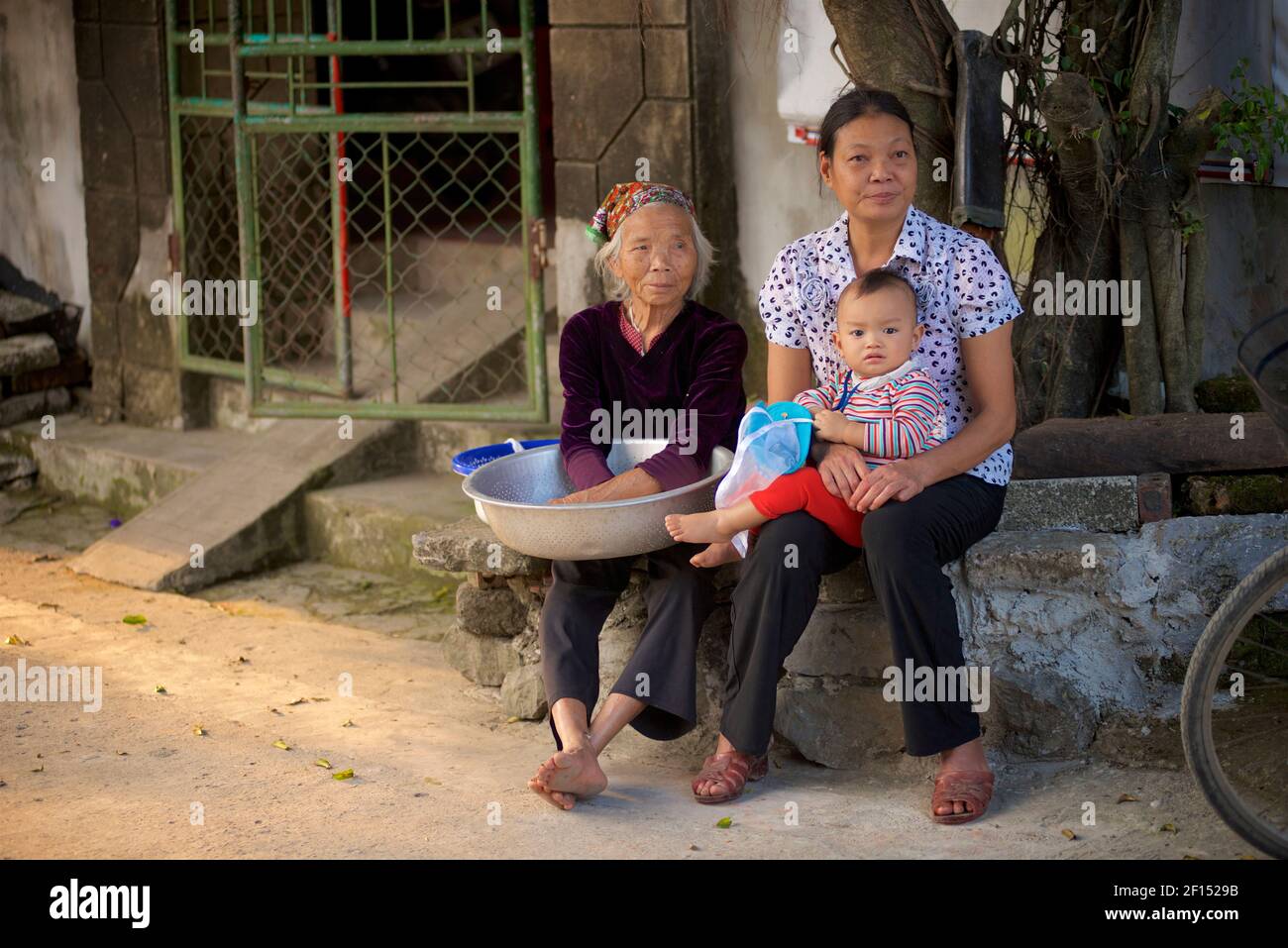 Vietnamese Grandmother, mother, daughter outside their home. Rural