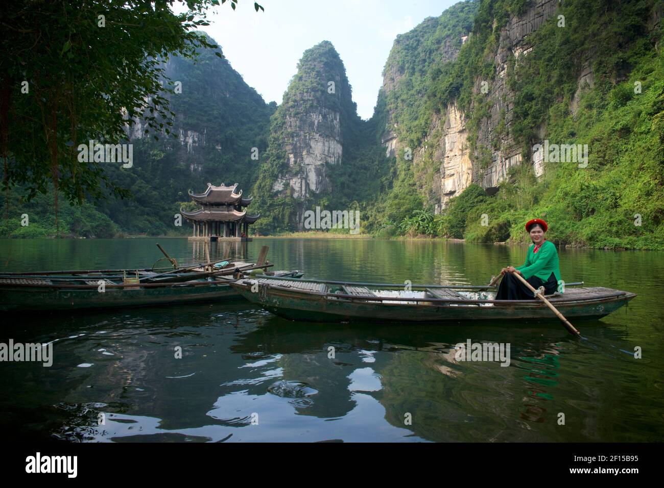 Vietnamese woman rowing boat. Travellng by river boat around the Trang An Scenic Landscape Complex, Ninh Binh, Vietnam Stock Photo