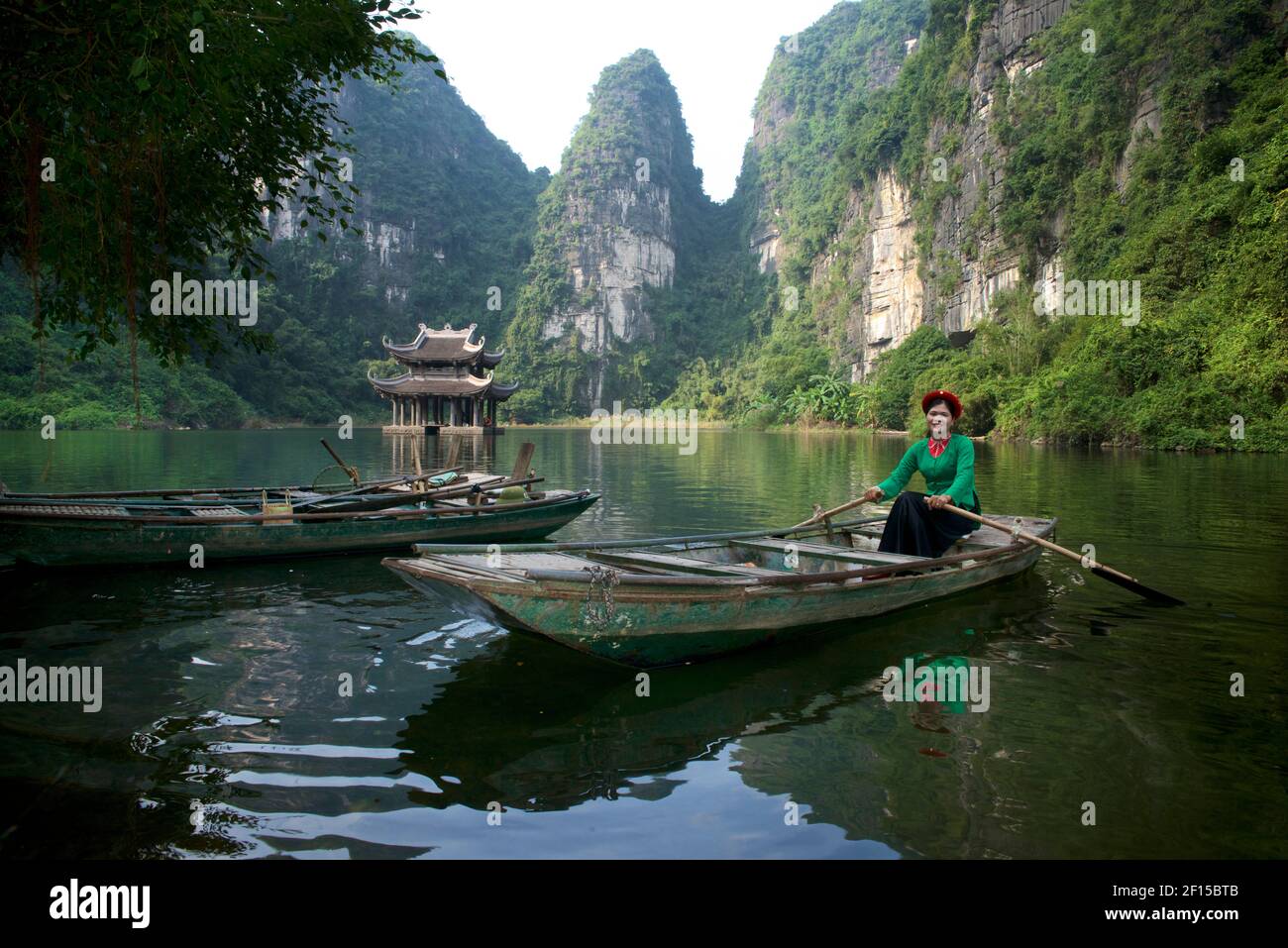 Vietnamese woman rowing boat. Travellng by river boat around the Trang An Scenic Landscape Complex, Ninh Binh, Vietnam Stock Photo